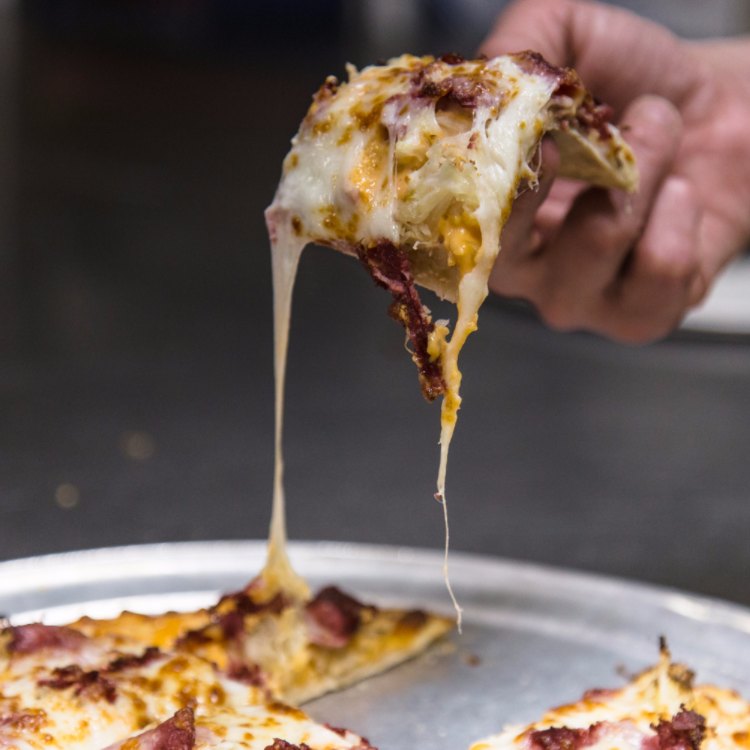 Cheesy pepperoni pizza slice being served at Angelo's Pizza